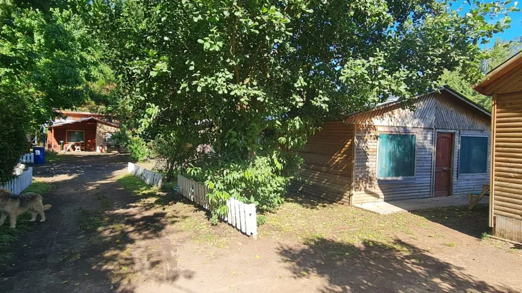 Exterior del complejo con cabaña de madera, jardín y valla blanca